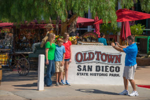 Family having picture taken next to Old Town San Diego State Historic Park sign